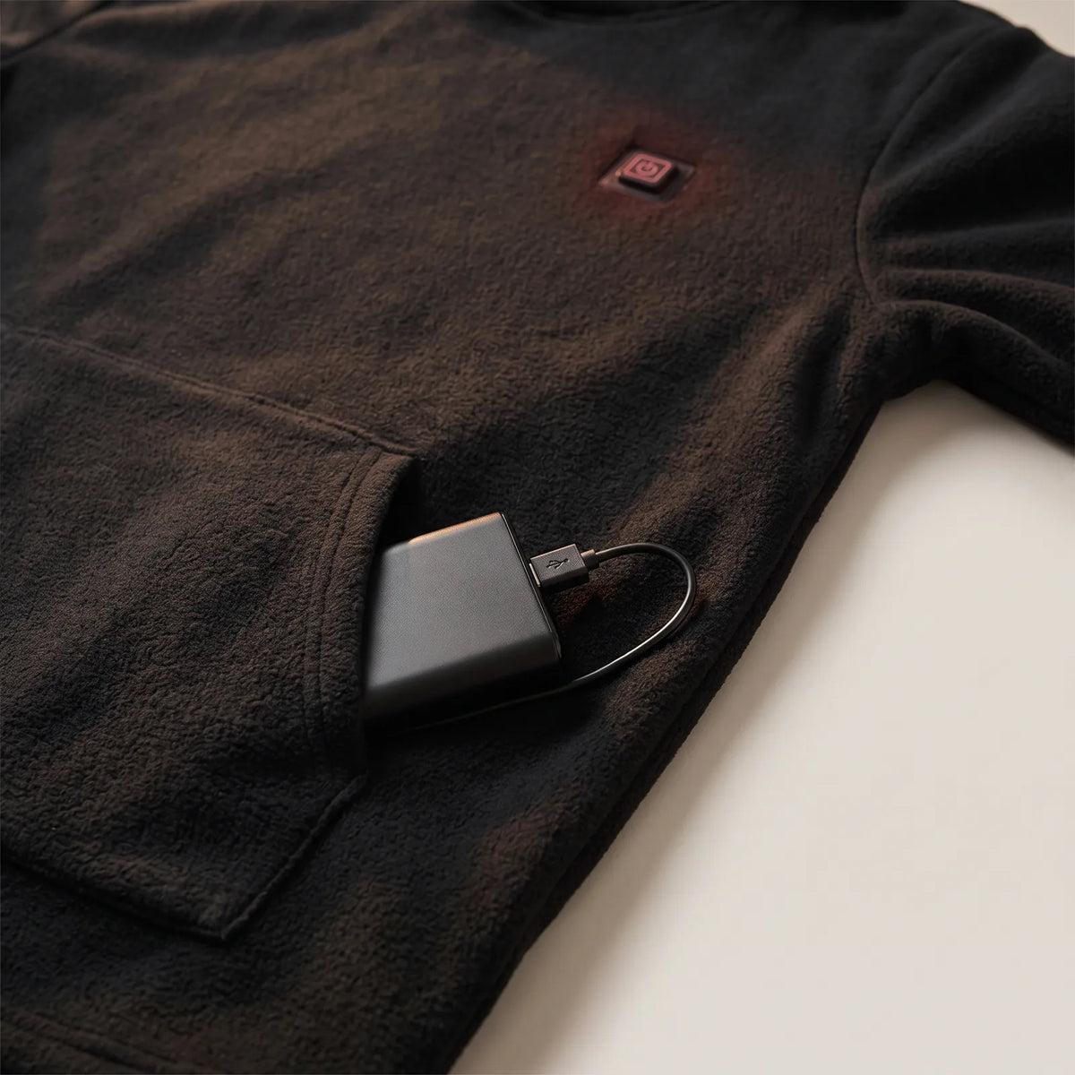 Powerbank mit USB-Kabel in der Kängurutasche des schwarzen Hoodies
